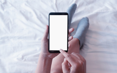 Mockup smartphone. Female holding cell phone with blank copy space screen for your promotional content. Woman using smart  phone while lying in bed.