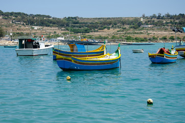 Traditional eyed colorful boats Luzzu in the Harbor of Mediterranean fishing village Marsaxlokk, Malta
