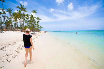 Teenage girl walking along sandy tropical Bavaro beach in Sargasso sea, Punta Cana, Dominican Republic