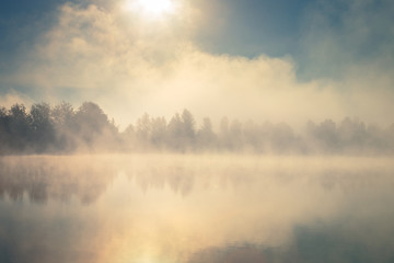 Fototapeta na wymiar Beautiful foggy morning. Lake coast. Fog over autumn lake water.