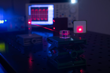 Experiment in optic lab with laser device. Red laser on optical table in physics laboratory