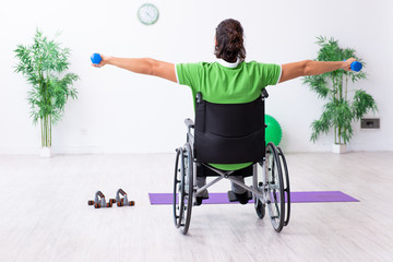 Young man in wheel-chair doing exercises indoors