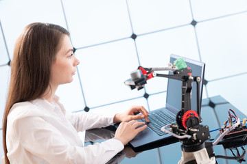 A young woman writes an algorithm for the robot arm. Science Research Laboratory for Robotic Arm...