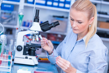 Laboratory assistant uses a polarizing microscope in a microbiological laboratory