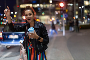 Woman calling taxi on city street at night