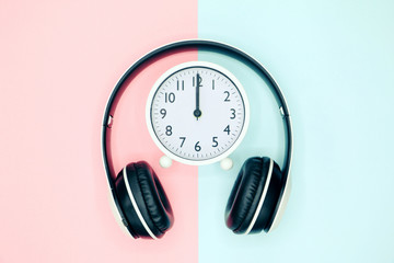 White headphones with alarm clock on Two colors background