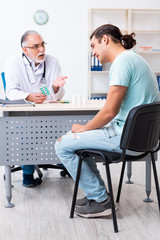 Obraz premium Young man visiting old male doctor