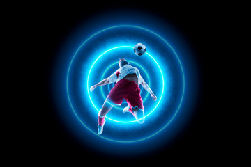 Footballer is dribbling with the ball. Blue neon light © Ruslan Shevchenko
