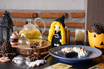 Halloween witchcraft tea party with herbal afternoon tea and macaron dessert in wicca and pegan concept with tarot cards. Selective focus on the Chrysanthemum tea. Cute crochet witch doll.