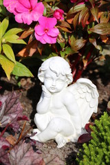 Ein Engel auf dem Friedhof zwischen Blumen schmückt ein Grab