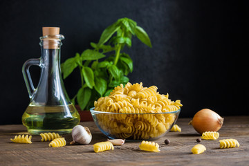 raw ingredients for cooking italian pasta. fusilli   garlic basil olive oil onion on wooden table...