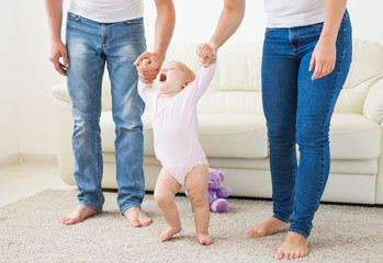 First steps of baby toddler learning to walk in white sunny living room. Footwear for child.