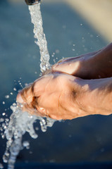 Female hand. Woman washes her hands under flowing water in a city fountain at the sports ground. Clear water is available everywhere in Spain. Clean hands and fresh skin.