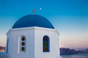 Fototapeta na wymiar Traditional dome of the churches at Oia City and the moon in Santorini Island