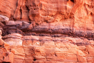 Jordan: rocky wall of the Wadi Rum desert mountains during sunset. Warm colors, red, yellow and purple.