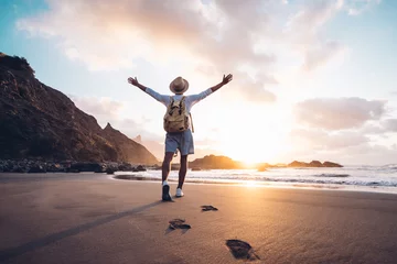 Fotobehang Young man arms outstretched by the sea at sunrise enjoying freedom and life, people travel wellbeing concept © Davide Angelini