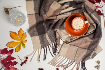 Autumn composition. Scarf, Cup of coffee with marshmallow, candle, Rowan and hawthorn berries, wild grass seeds on a white background.
