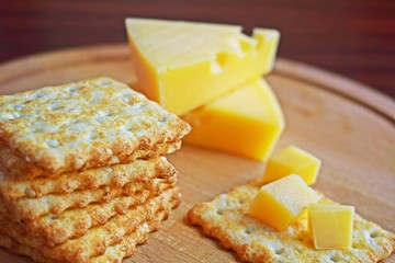 Fresh crispy cracker with cheese and sesame on wooden background.