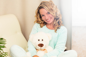 Portrait of a beautiful, sexy, sweet, gentle girl with a white cozy Bear at home in pajamas.