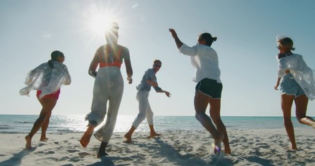 Slow motion of young multi-ethnic friends  are having fun to enjoy their summer vacation together on a beach with a sea in a sunny day.
