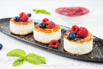 Small cottage cheese pancakes with berries on a white background.