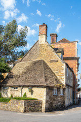 Old buildings in an English village with multiple chimneys under a pretty blue cloudy sky