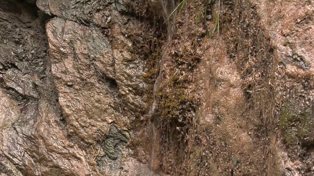 After heavy rain in the Alps, water is running down mountainsides, dripping from stone overhang, or pouring down over open rock face. Collection of three shots.