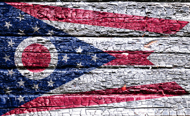 The national flag of the US state Ohio in against a black charred wooden wall on the day of...