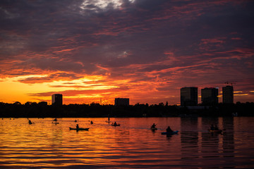 Fototapeta na wymiar Bucharest sunset on Herastrau lake with kayak , people having relaxing and fun time 