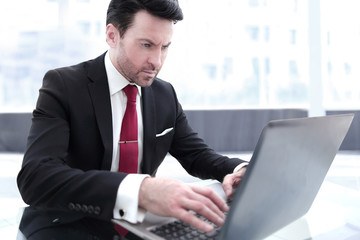 Businessman typing on a laptop, sitting at his Desk