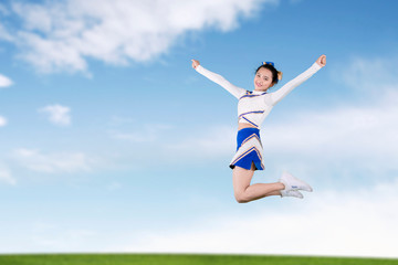 Beautiful cheerleader leaping in the meadow