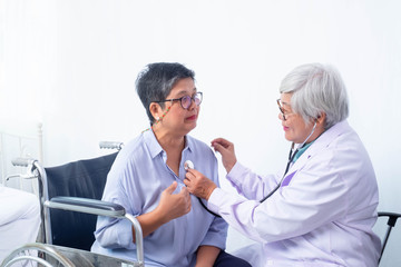 Fototapeta premium Senior physicians are expert for Asian seniors, check symptoms after treatment, use medical stethoscope, patients show facial expressions. sitting in a wheelchair, concept patient help care center.