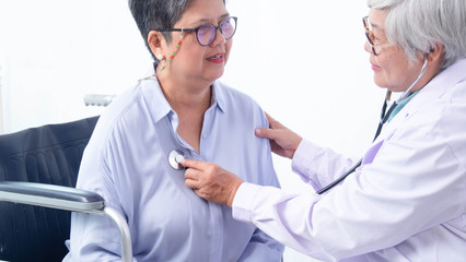 Asian medical professionals are checking their health, using medical stethoscope for an old woman sitting in a wheelchair, patients with walking problems and overweight.