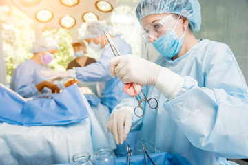 Surgeon and assistants in operating room with surgery equipment.