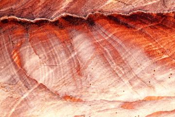 Jordan: rock face of Petra, with streaks that form red, white and yellow waves. Warm light, background, wallpaper.