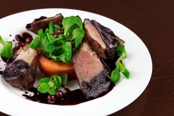 baked duck fillet in a sauce with herbs and berries in a plate