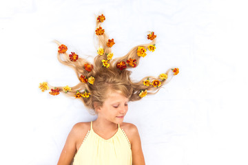 Obraz na płótnie Canvas charming smiling child with healthy and strong long blond hair in shape of spike with floral arrangement
