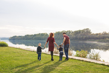 Parent, childhood and nature concept - Family playing with two sons by the water