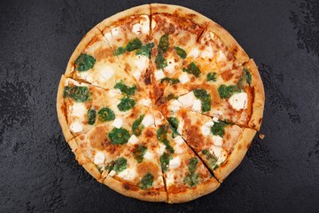 Hot four cheese delicious pizza with a thick crust on a black texture background.