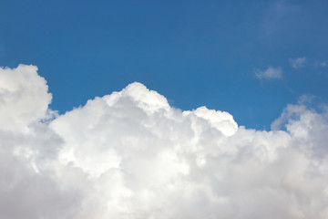 Fototapeta na wymiar Big fluffy white clouds against a bright clear blue sky background