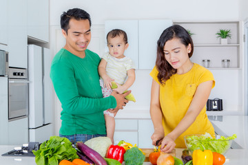 Mother prepares salad with her husband and baby