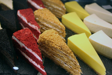 Triangular pieces of cake lie on a dark background. Red, yellow, sand-colored pieces of cake.