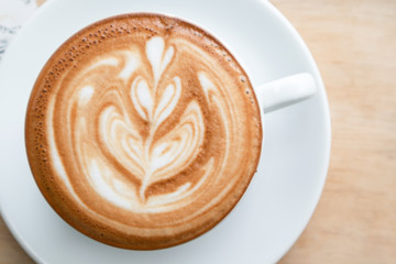 Coffee cup latte art in heart shape on wooden table.Frothy drink for coffee break after working or weekend meeting