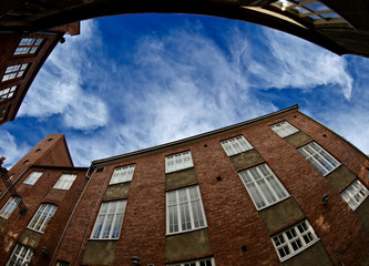 A fish eye image of an old factory building with blue sky above
