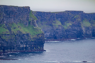 Stunning view of the vertical walls of the Cliffs of Moher on a cloudy day with fog, geosites and...