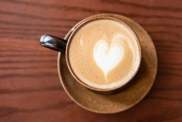 Coffee cup latte art on wooden table background.frothy milk texture on arabica coffee for coffee break time.