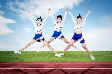 Pretty cheerleader team performing in the field