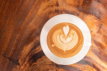 Coffee cup latte art in heart shape with a cup of dark coffee and dark chocolate on wooden table.Frothy drink for coffee break after working or weekend meeting
