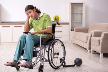 Young male invalid in wheel-chair suffering at home