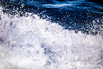 A close up shot of the blue waters of a rough sea with splashes, foam and waves in the Atlantic Ocean in Ireland